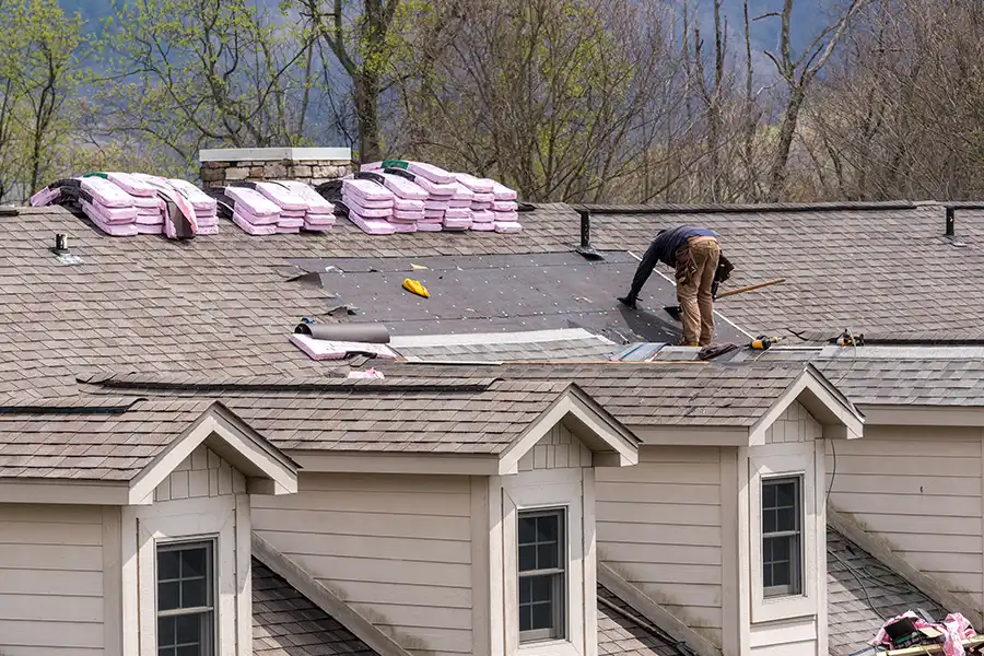 Capital City Roofing & Solar—A roofing contractor removing the old shingles before replacing them with new shingles on a townhouse roof in Central IL.